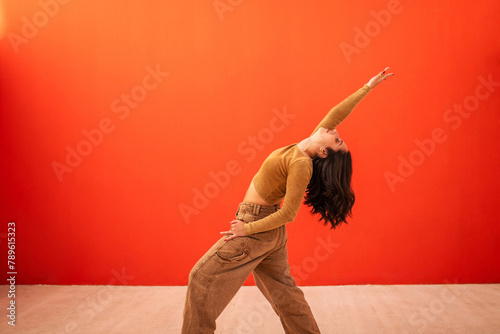 young generation z woman dancing in front of an orange background photo