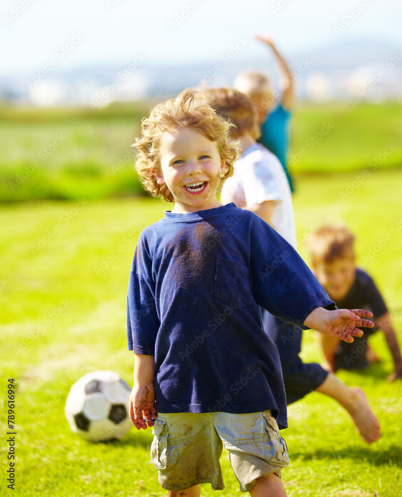 Obraz premium Dirt, smile and portrait of child for soccer by grass, lawn and outdoor playing with happiness in nature. Boy, freedom or fun in football for activity, comic and excited in youth outside with friends