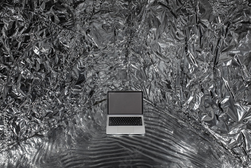 a mockup with a laptop in a space made of crumpled metallized material photo