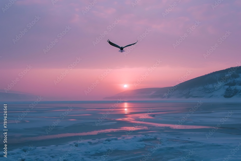 : Sunrise over a frozen lake with a lone bird soaring across the sky.