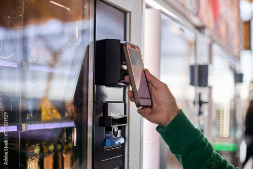 A man paying with his mobile phone at a vending machine.