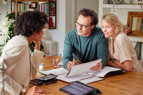 Happy couple having finance discussion with consultant at home photo