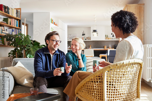 Smiling couple with female insurance agent at home photo