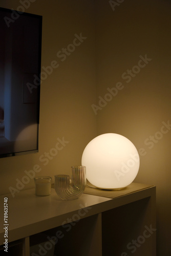 Round table lamp lights up in the night on the shelf photo