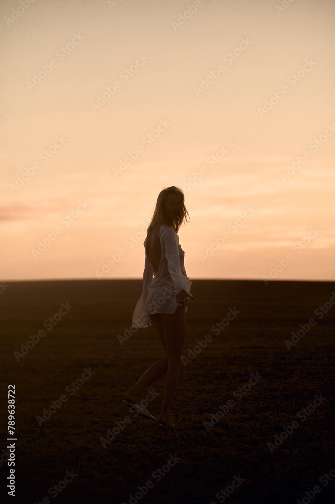 silhouette of a woman walking in the field at sunset silhouette of a woman walking in the field at sunset