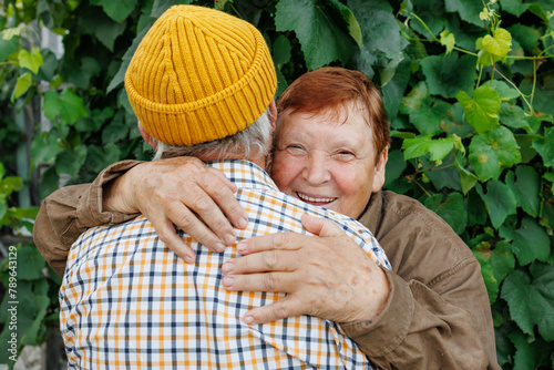 An elderly couple exchanges a warm embrace outdoors  photo