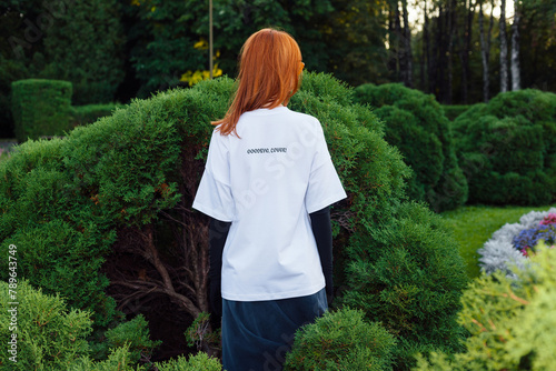 Young woman in white t-shirt backside fashion style posing in park