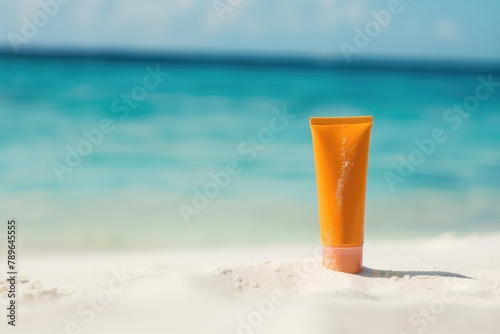 blank sunscreen orange tube on clear white sand; blue ocean on blurred background, copy space