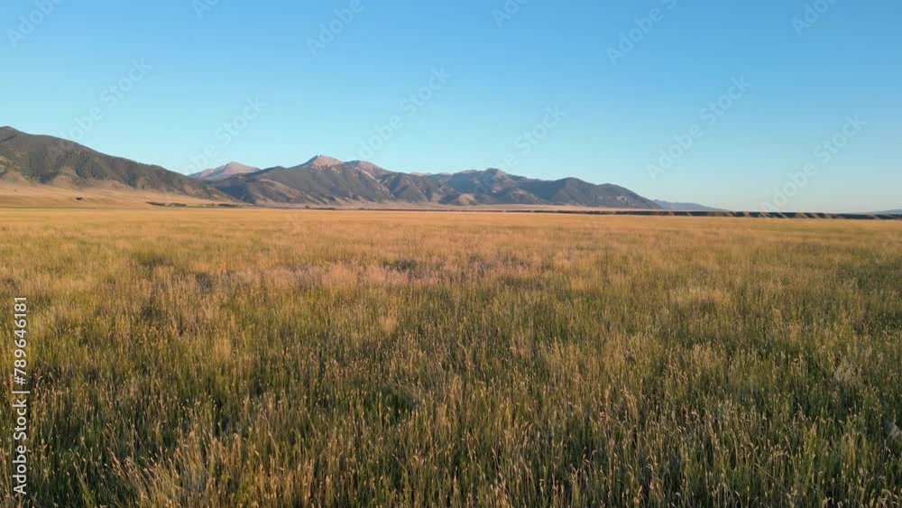 Grass bench valley aerial flyover with mountains in the distance in Ennis Montana Grass bench valley aerial flyover with mountains in the distance in Ennis Montana