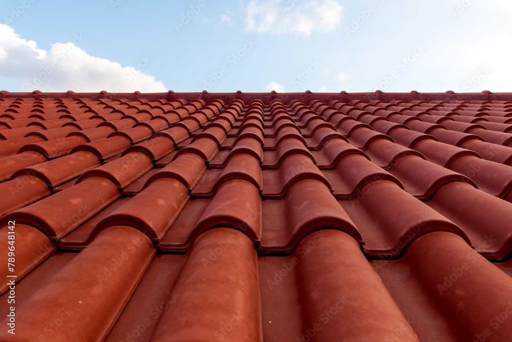 Red tile roof under blue sky. One part is a roof and the other is a pure blue sky.