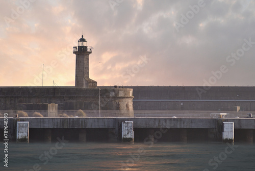 Old and aged lighthouse with sunset, ocean water movement in motion blur