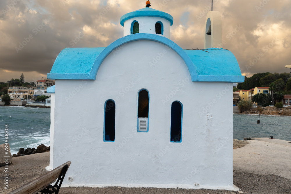 Beautiful chapel on the coast on Crete on rays of sunrise.