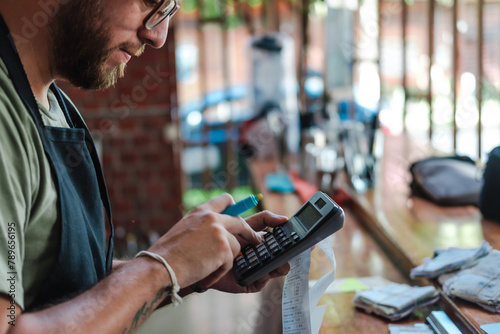 man using calculator and holding a receipt photo