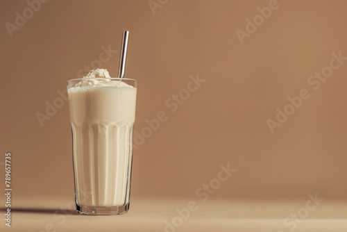 vanilla protein shake in glass with whipped cream and metal straw on warm beige background, copy space for text photo