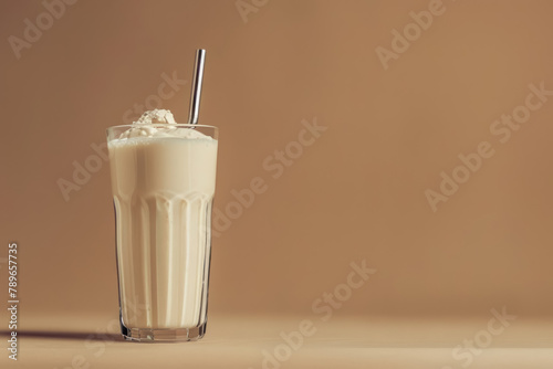 vanilla protein shake in glass with whipped cream and metal straw on warm beige background, copy space for text