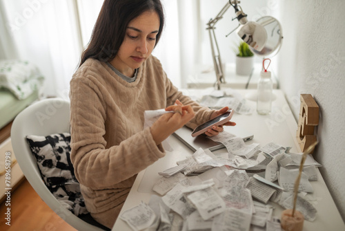 Teenage girl placing purchase receipts on her bedroom desk photo