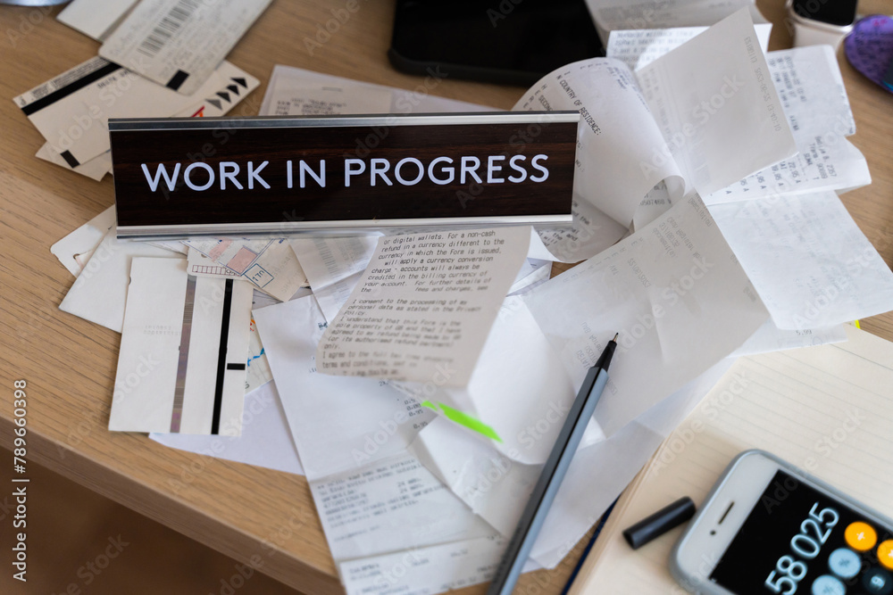 Messy workplace desk with utility bills, tax forms, invoices, receipts ...