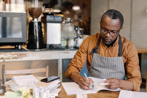 Entrepreneur Calculating Expenses in Café
 photo