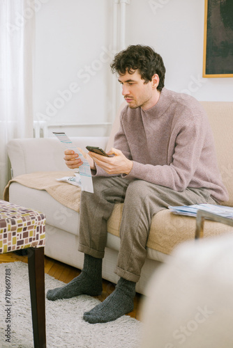 Young man pays utility bills via smartphone 