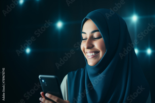 smiling young arab woman with headscarf looking at her smart phone