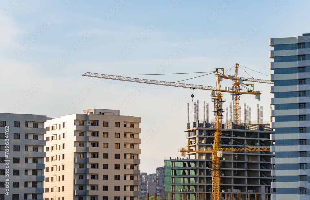 Crane next to high-rise building, construction concept Crane next to high-rise building, construction concept