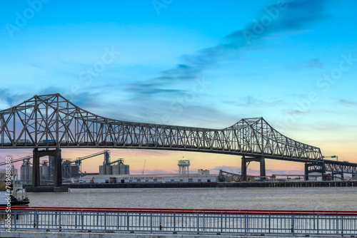 The Horace Wilkinson Bridge over the flowing waters off the Mississippi River with boats on the water, lush green grass and clouds at Louisiana Memorial Plaza in Baton Rouge Louisiana USA