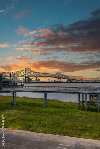 The Horace Wilkinson Bridge over the flowing waters off the Mississippi River with boats on the water  lush green grass and clouds at Louisiana Memorial Plaza in Baton Rouge Louisiana USA