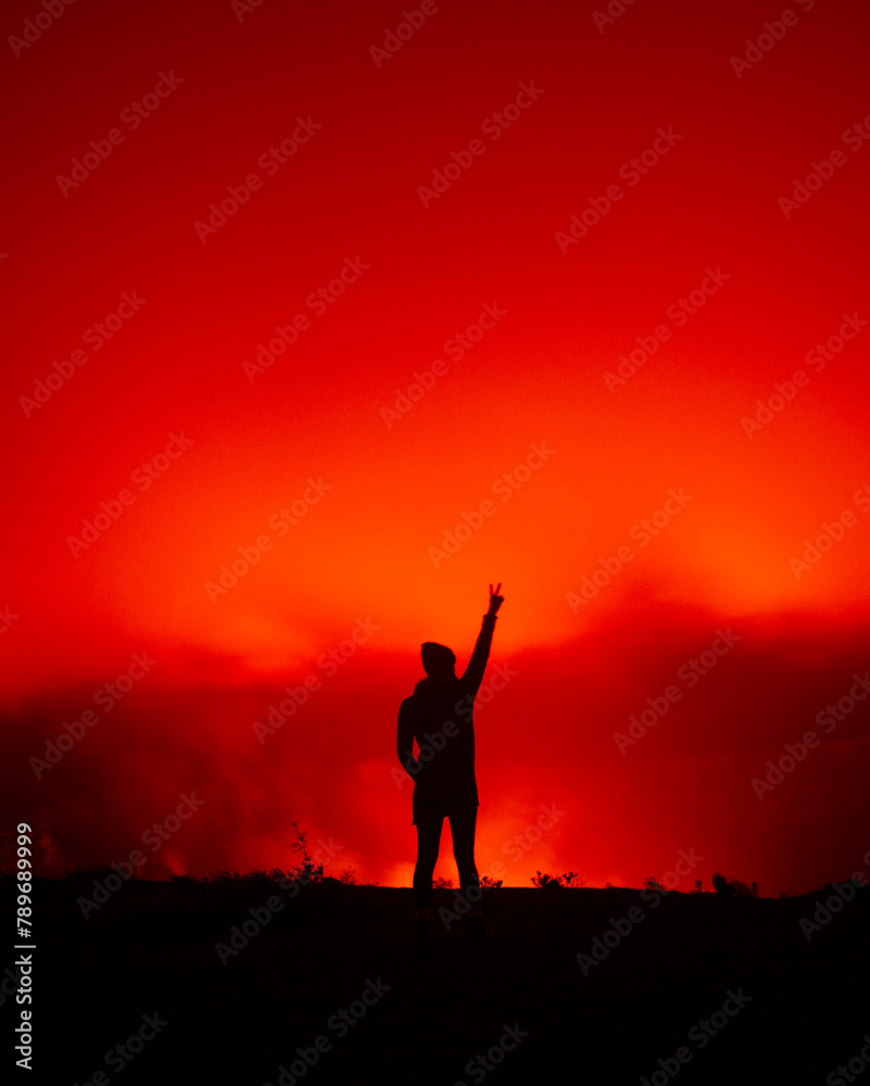 Silhouette of Woman Giving Peace Sign with Glow of Volcano at Night Silhouette of Woman Giving Peace Sign with Glow of Volcano at Night