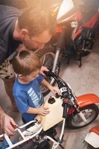 Dad, child and fixing with bike in garage at home for teamwork, support and repair with tools to educate. Family, father and son for bonding, helping and together as mechanic for motorbike in carport