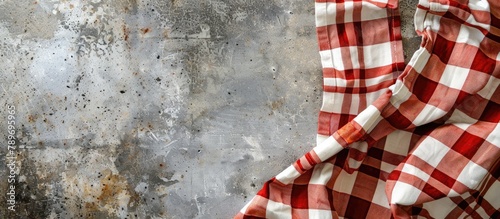 Checkered kitchen tablecloth seen from above on a concrete background.