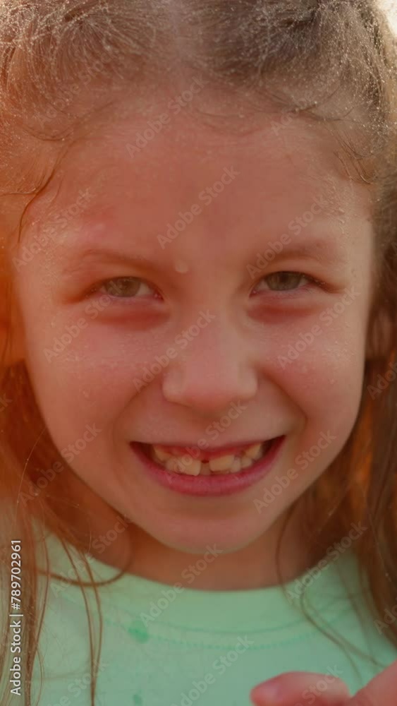 Charming child stands beneath gentle rain. Small girl eyes sparkling with wonder at rural nature display at sunset. Gap-toothed smile infects with happiness Charming child stands beneath gentle rain. Small girl eyes sparkling with wonder at rural nature display at sunset. Gap-toothed smile infects with happiness