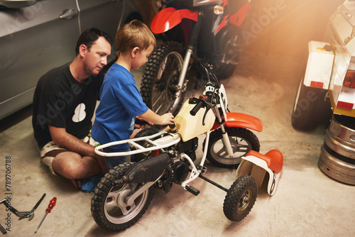 Parent, child and fixing bike in garage at home for teamwork, support and repair with tools. Family man, father and son for bonding, helping and together as mechanic for motorbike in carport