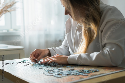 Young woman doing jigsaw puzzle at home photo