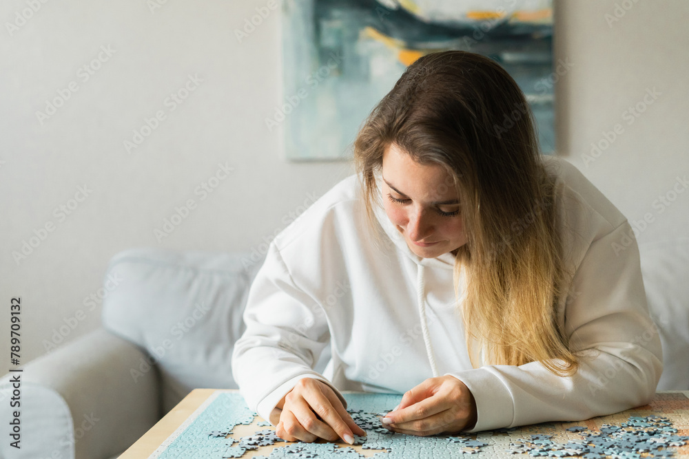 Young woman in assembling jigsaw puzzle at home Young woman in assembling jigsaw puzzle at home
