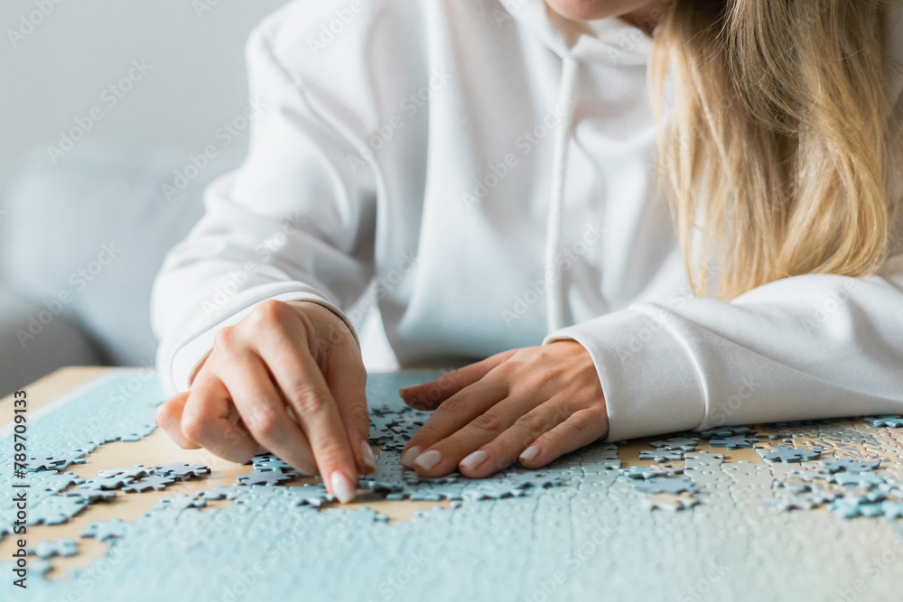 A close-up of female hands doing a jigsaw puzzle A close-up of female hands doing a jigsaw puzzle
