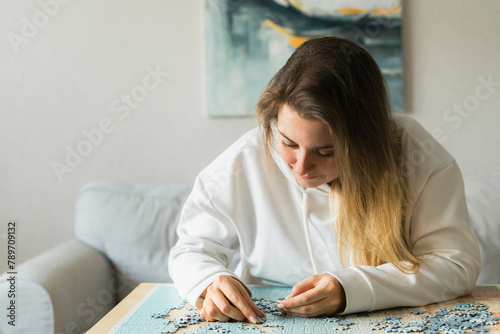Young woman in assembling jigsaw puzzle at home