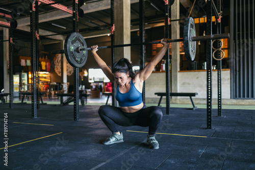 Asian woman doing a snatch in the gym photo