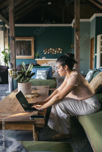 Woman working remotely from the common area of a hostel photo
