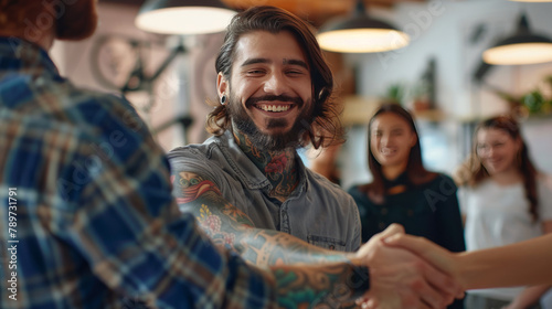 Portrait of modern business team welcoming new employee focus on smiling tattooed man shaking hands with intern photo