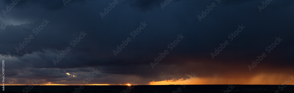 Landscape at sunset. A thunderstorm is approaching the village. Tragic gloomy sky. Panorama.