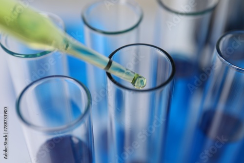 Laboratory analysis. Dripping liquid into test tubes indoors, closeup