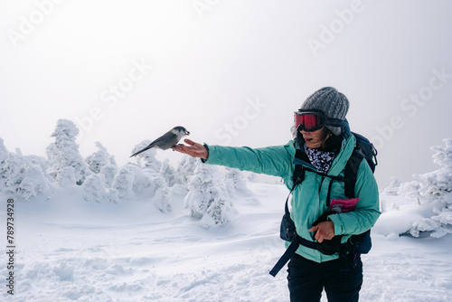 hiker feeding bird  in frozen landscape in White Mountains NH
