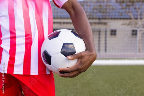 An African American young male athlete in striped red and white soccer uniform holding a soccer ball © wavebreak3