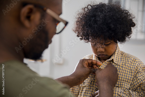 Father buttoning shirt of son at home photo