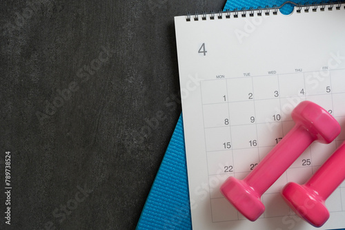 Time for exercising equipment dumbbell and calendar with black background, sport and healthy concept