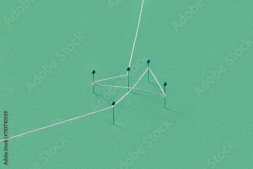 Several stationery pins stuck in green paper and tied with thread