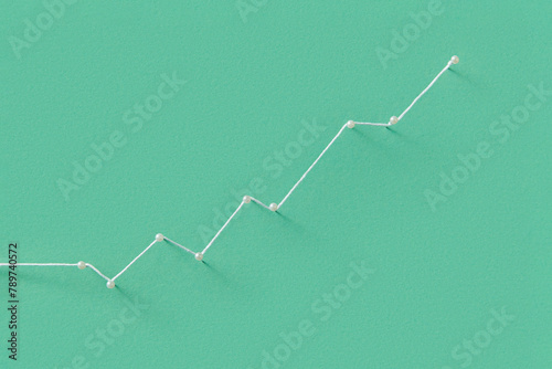 Stationery pins tied with white string on green paper background photo