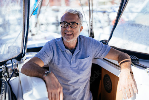 Positive sale man sitting in yacht on sunny day photo