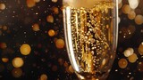 Close-up of glass with sparkling liquid and bubbles against bokeh background warm tones