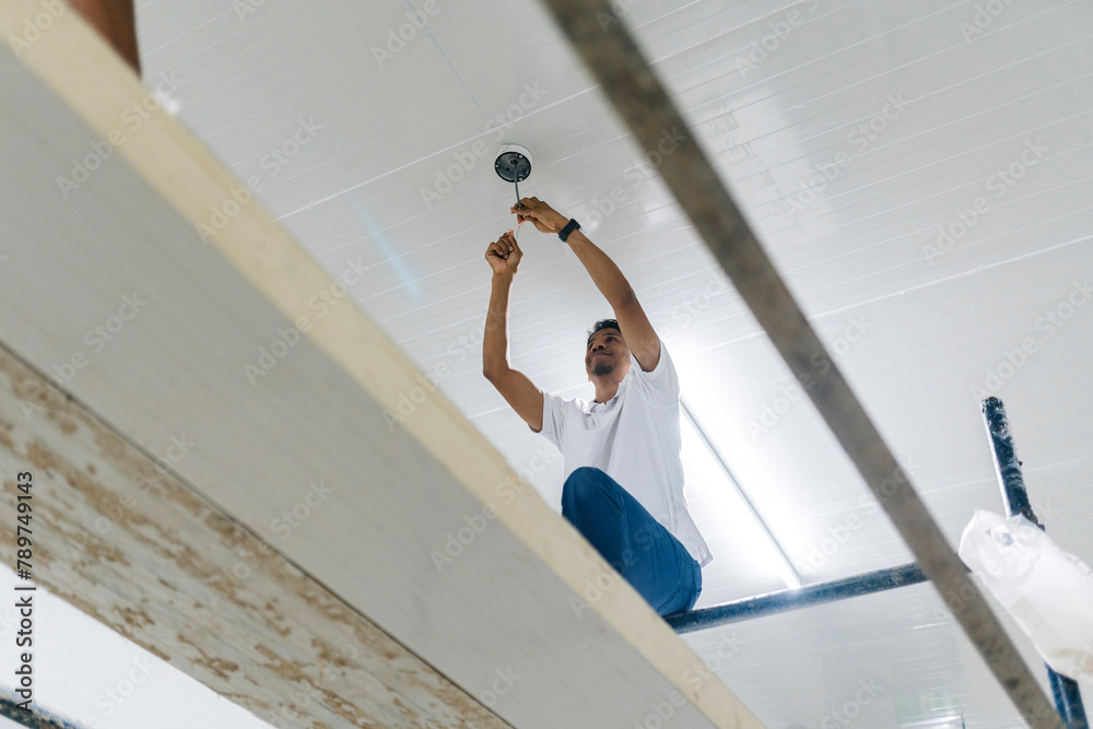 Focused male worker installing security camera Focused male worker installing security camera